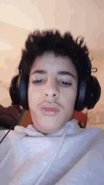 a young man wearing headphones and making a funny face .