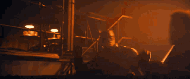 a man in a cape stands in a dark room with a scaffolding in the background