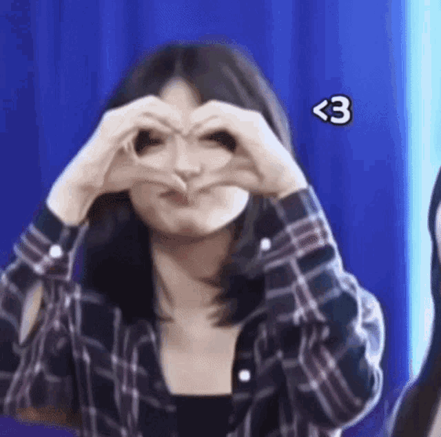 a girl is making a heart shape with her hands .