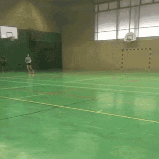 a person is playing basketball in a gym with a basketball hoop in the background