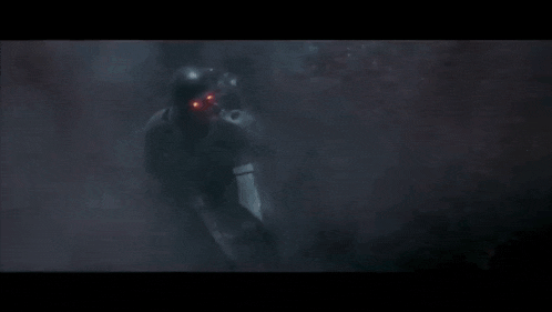 a man in a helmet is holding a gun with a flame coming out of it .
