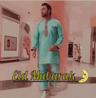 a man in a white robe is standing next to a sign that says eid mubarak
