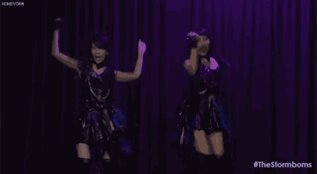 two women are dancing on a stage in front of a blue curtain with the hashtag #thestormbombs