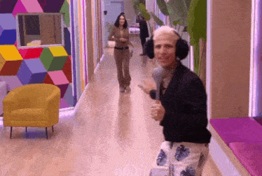 a man wearing headphones is dancing in a hallway with a woman walking behind him