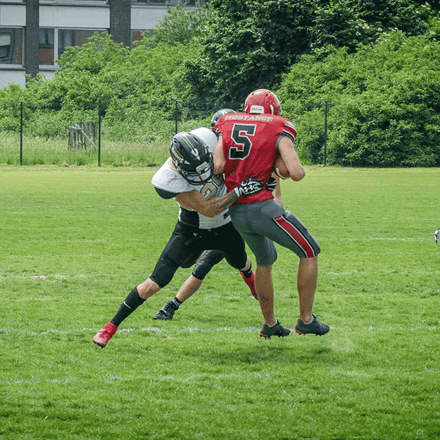 a football player with the number 5 on his jersey is being tackled