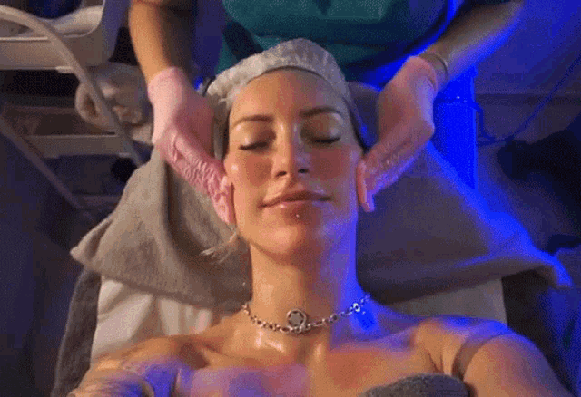 a woman with her eyes closed is getting a head massage