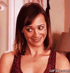a woman is smiling and looking at the camera while wearing a necklace .