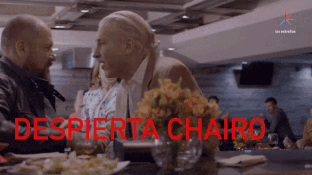 a group of people sitting at a table with the words " despierta chairo " written in red