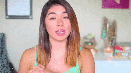 a woman in a green tank top is making a funny face .