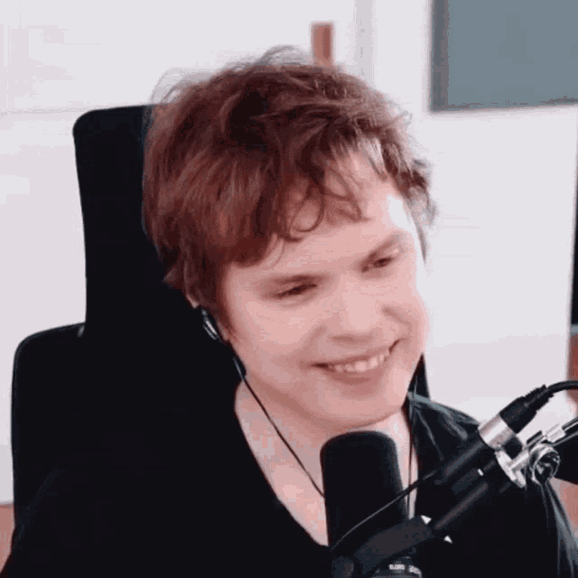 a young man is smiling in front of a microphone and wearing headphones