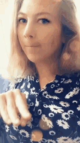 a woman with a nose ring is wearing a blue and white floral shirt .