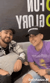 two men are sitting on a couch in front of a sign that says " yao ia "