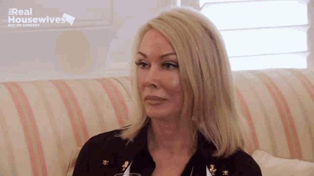 a woman sits on a striped couch with a real housewives logo behind her