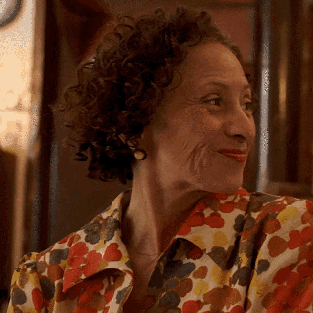 a woman with curly hair is wearing a colorful shirt