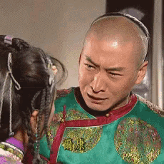 a bald man in a green and red outfit is looking at a woman