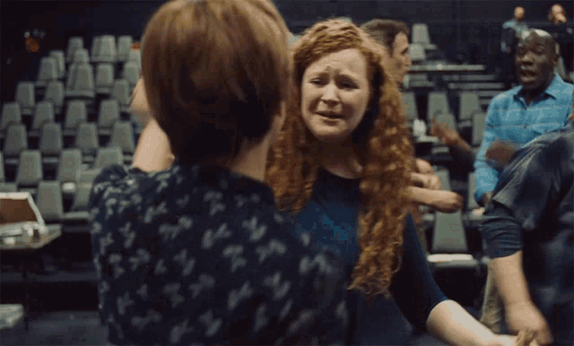a woman with red hair is crying while another woman holds her arm up