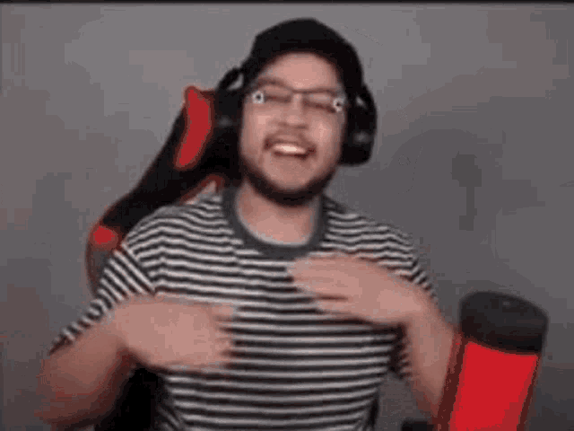 a man wearing headphones and glasses is sitting in front of a microphone in a chair .