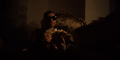 a man in a ny yankees shirt is holding a bunch of money in his hands