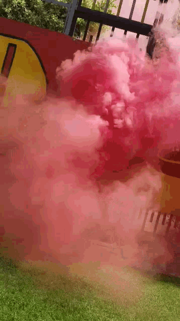 a bunch of pink smoke is coming out of a yellow and red object