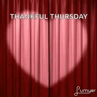 a red curtain with a heart shaped shadow on it and the words `` thankful thursday '' written on it .