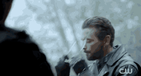 a man with a beard is holding a knife in his hand and looking at another man .