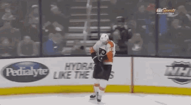 a hockey player is skating on the ice in front of a pedialyte advertisement .