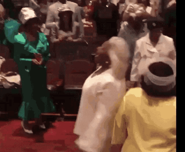 a woman in a green dress is dancing in a crowd of people
