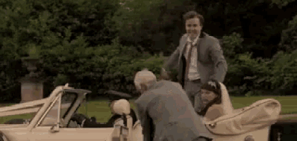 a man in a suit and tie is standing next to a bride in a wedding car .
