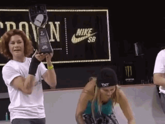 a person holding a trophy in front of a sign that says " nike sb "