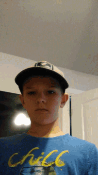 a boy wearing a hat and a blue shirt that says ' chill '