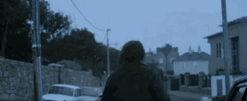 a woman is walking down a street with a car in the foreground .