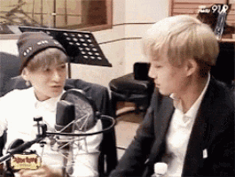 two young men are sitting in front of a microphone .