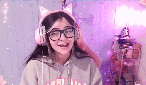 a girl wearing headphones and a cat ear headband is smiling .