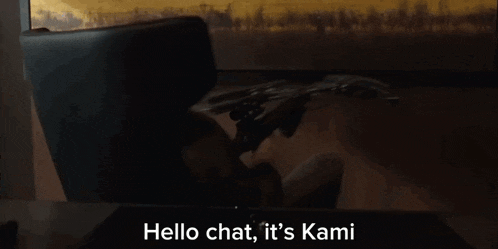 a man sitting at a desk holding a sword with the words hello chat it 's kami below him