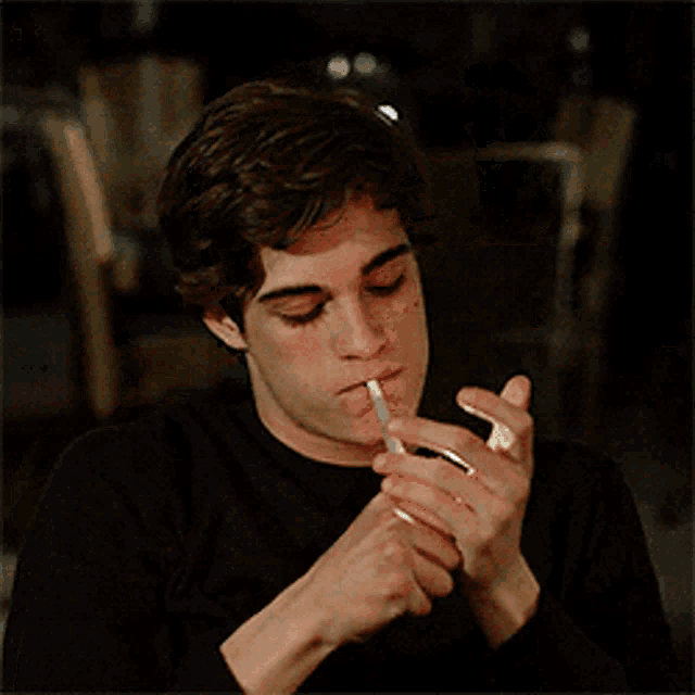 a young man is smoking a cigarette with smoke coming out of his mouth