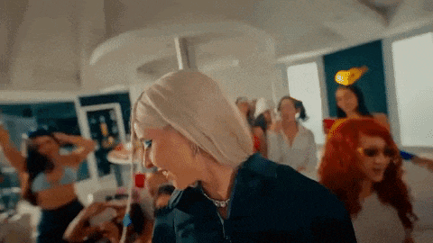 a woman with blonde hair is standing in front of a crowd of people .