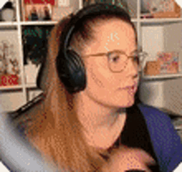 a woman wearing glasses and headphones is sitting in front of a shelf .