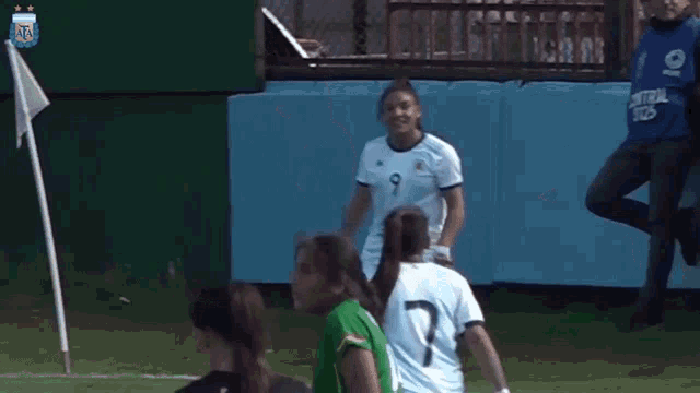 a girl in a green number 14 jersey stands in front of a group of girls