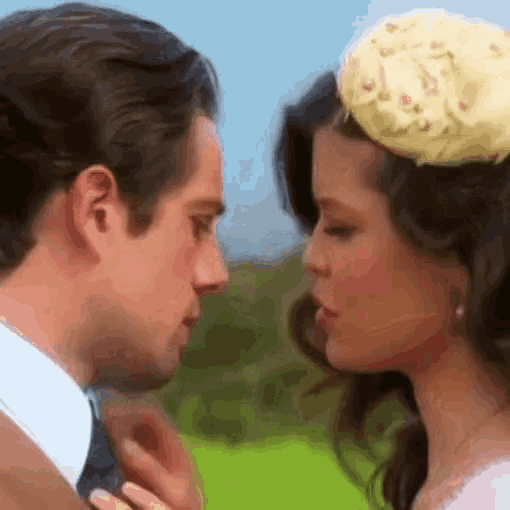 a man and a woman are looking at each other and the woman is wearing a hat