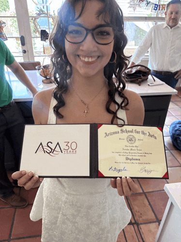 a woman is holding up a certificate from the arizona school for the arts