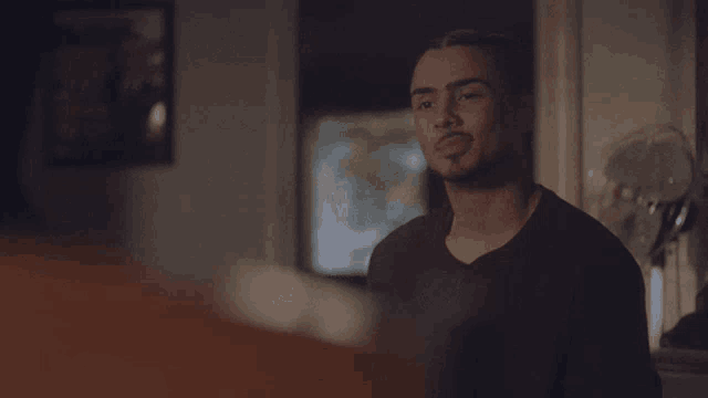 a man in a black shirt is smiling with his eyes closed in a dark room