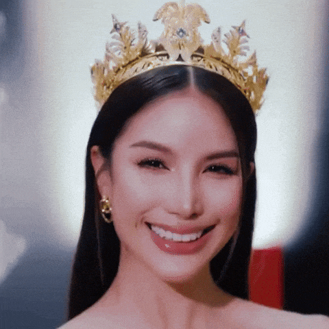 a woman wearing a gold crown and earrings smiles for the camera