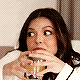 a woman is drinking a glass of wine and making a face .