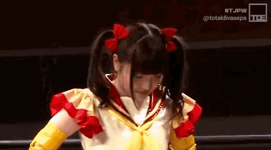 a girl with pigtails and a sailor suit is standing in a wrestling ring .