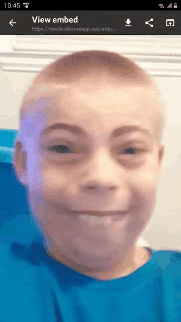 a phone screen shows a picture of a young boy making a funny face .