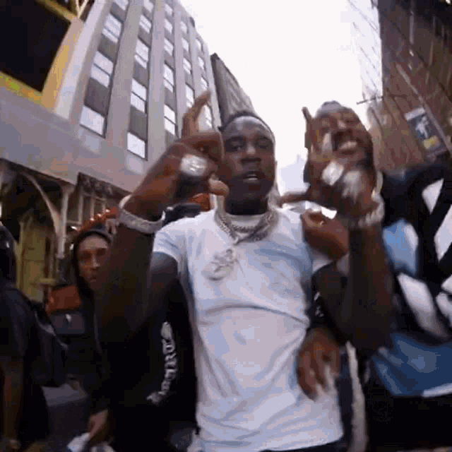 a group of men are standing on a city street making a funny face .