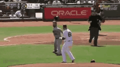 a baseball game is being played on a field with an oracle sign in the background .