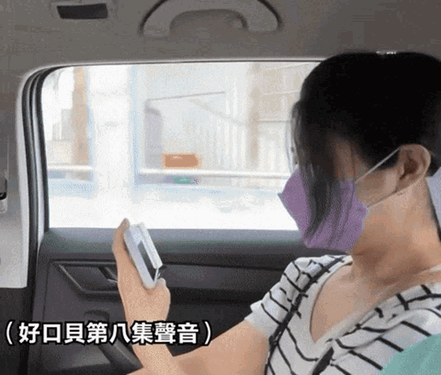 a woman wearing a purple mask holds a cell phone