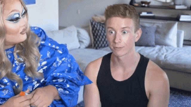 a man in a black tank top is sitting next to a woman in a blue dress