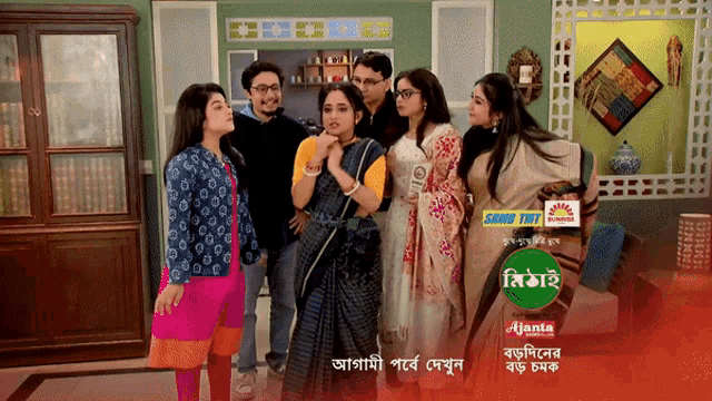 a group of people standing in a living room with a green circle that says ' ajant ' on it